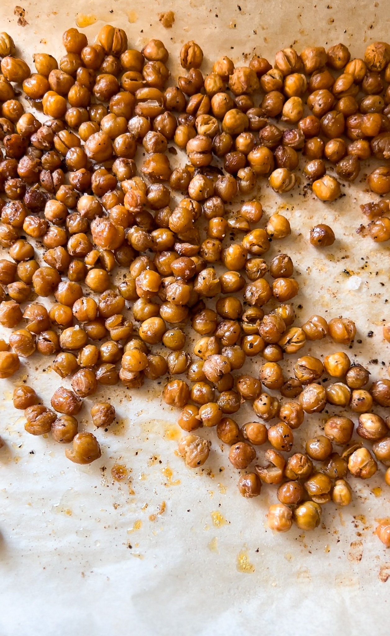 A rimmed baking sheet is lined with crispy roast chickpeas from the oven.