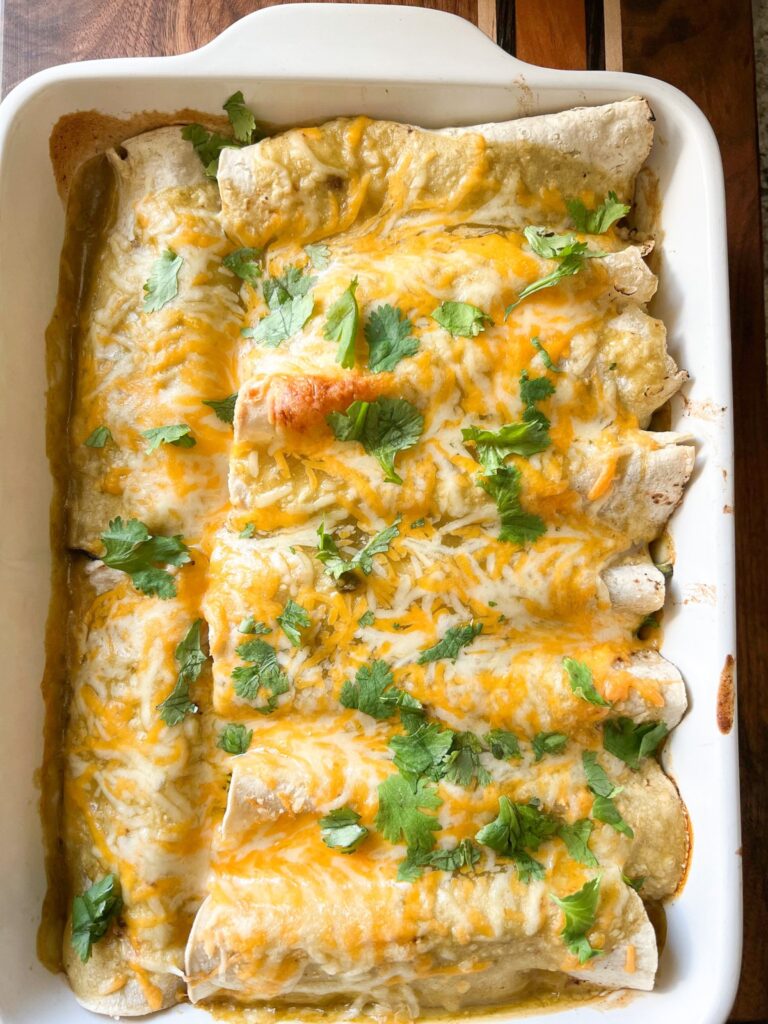 A flatlay image of freshly baked veggie enchiladas filled with seasonal vegetables and topped with our favorite salsa verde.