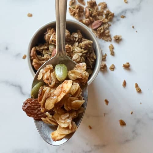 A silver spoon holds a teaspoon of homemade granola.