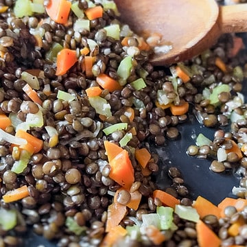 Nonstick skillet filled with braised lentils.