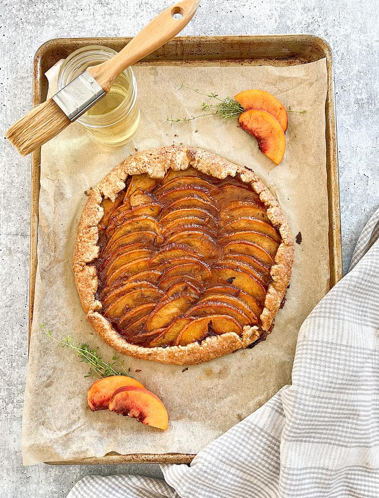 The Best Rustic Peach and Thyme Galette post bake is brushed with thyme simple syrup. 