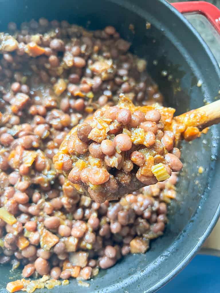 A large dutch oven is filled with stewed Santa Maria-Style Pinquito Beans. 