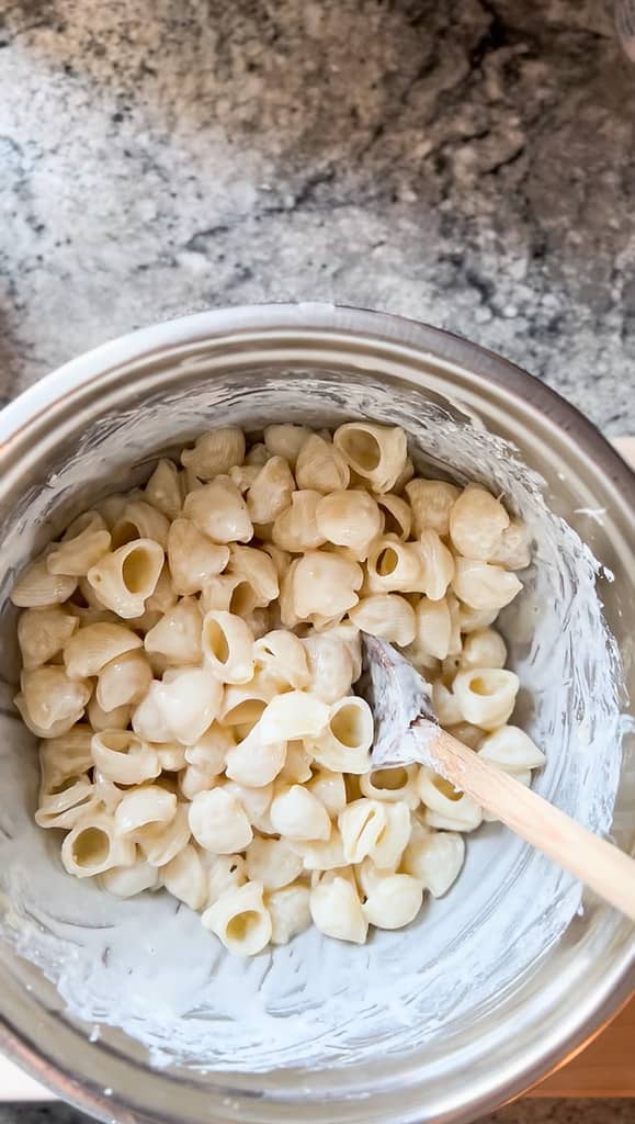 A large prep bowl contains cooked pasta tossed in a whipped ricotta sauce ready to be combined with caramelized zucchini. 