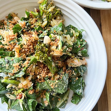 A large white bowl holds broccolini and beans pasta salad made with broccolini, broccoli greens, white beans and crispy breadcrumbs tossed in a lemon parmesan vinaigrette.