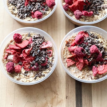 4 small containers hold 8 ounces each of Chocolate Berry Overnight Oats topped with dried berries.