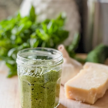 A small glass jar is filled with Zucchini and Basil Pesto.