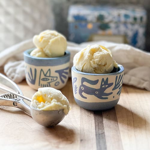 Two small ceramic cups positioned side by side hold generous scoops of vanilla bean ice cream.