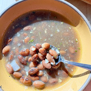 A bowl of beans in their bean broth cooked with shallots, garlic, and herbs.