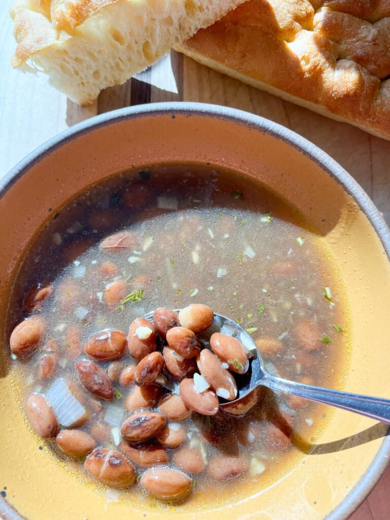 A bowl of beans in their bean broth cooked with shallots, garlic, and herbs. 