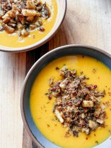 Two bowls hold generous servings of the Spiced Squash Soup and are topped with crispy herbed mushrooms.