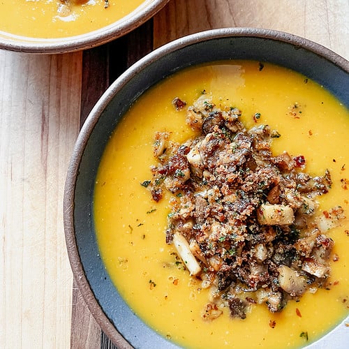 Two bowls hold generous servings of the Spiced Squash Soup and are topped with crispy herbed mushrooms.
