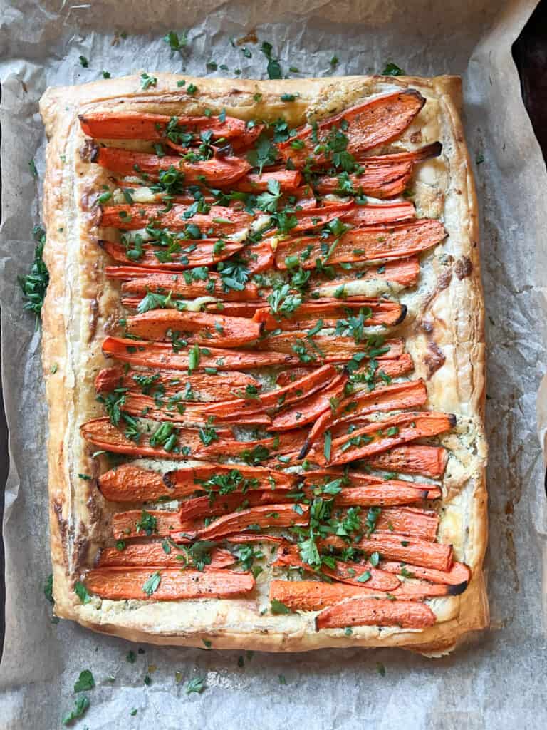 A flatlay image of the Roast Carrot Tart in Puff Pastry with golden brown edges and caramelized roasted carrots. 