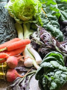 Portrait photo of early winter produce from Stepping Stone Farm CSA for Dinner Plans Week 52 featuring: Napa cabbage, mustard greens, chard, kale, carrots, golden beets, and leeks.