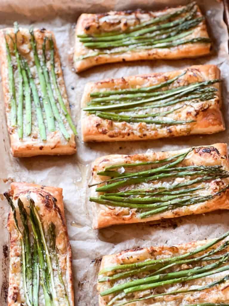 Portrait photo of prepared Asparagus Tart with Puff Pastry freshly baked to golden brown and crispy. Asparagus spears have been roasted in a creme fraîche flavored with caramelized shallot and spring onion.