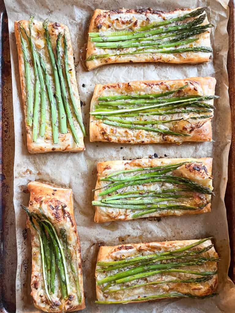 Portrait photo of prepared Asparagus Tart with Puff Pastry freshly baked to golden brown and crispy. Asparagus spears have been roasted in a creme fraîche flavored with caramelized shallot and spring onion.