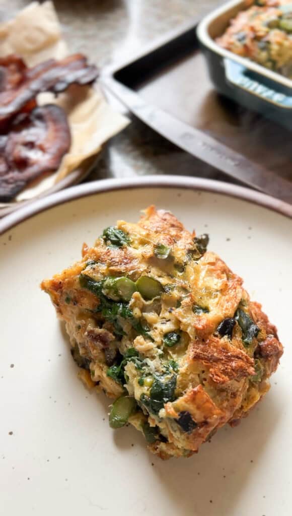 Portrait image of a slice of the Breakfast Strata for Two that's generously served on a wide rimmed ceramic plate.