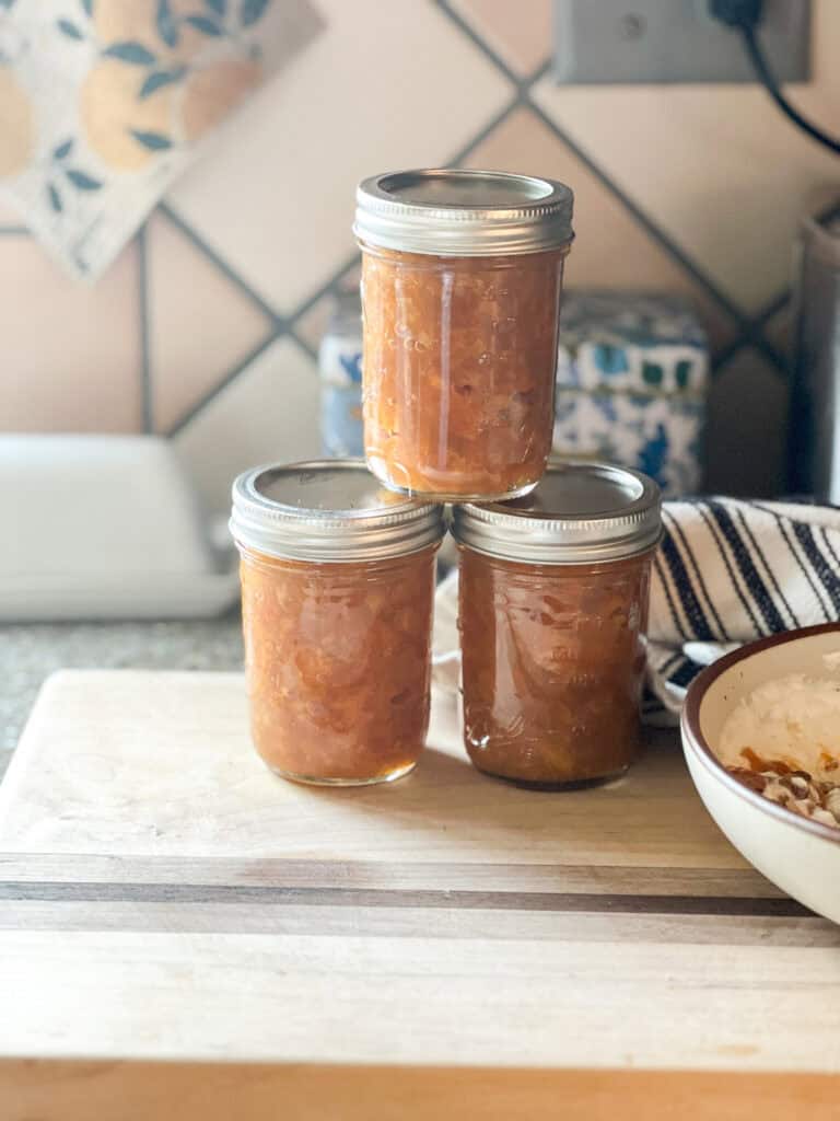 Front facing photo of 3 jars of finished Mandarin Marmalade. Jars have been sealed and will be stored in the freezer for future months.