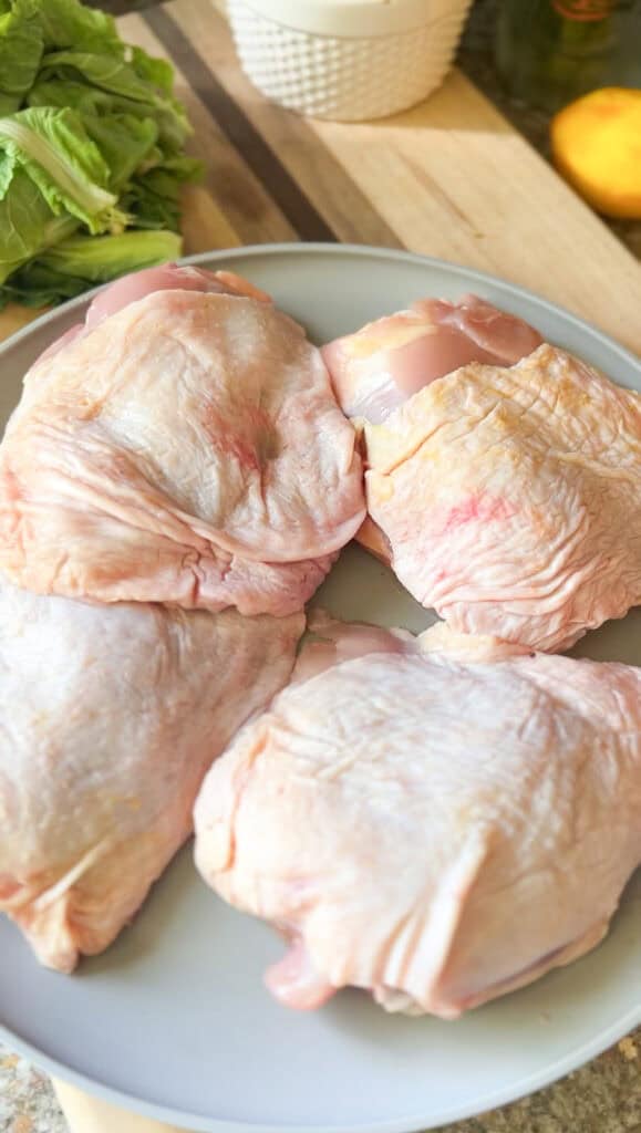 Portrait photo of 4 bone-in chicken thighs that are not yet seasoned for this French Roast Chicken Recipe.