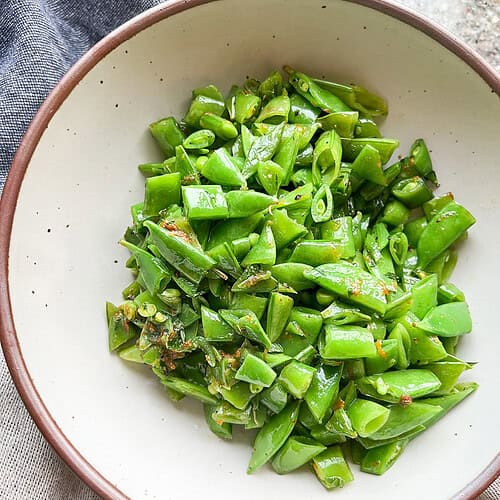Close up Portrait photo of sautéed sugar snap peas with fresh citrus zest and mint.