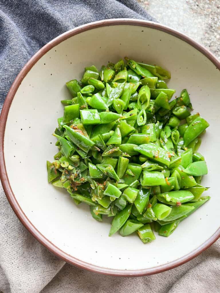 Close up Portrait photo of sautéed sugar snap peas with fresh citrus zest and mint.