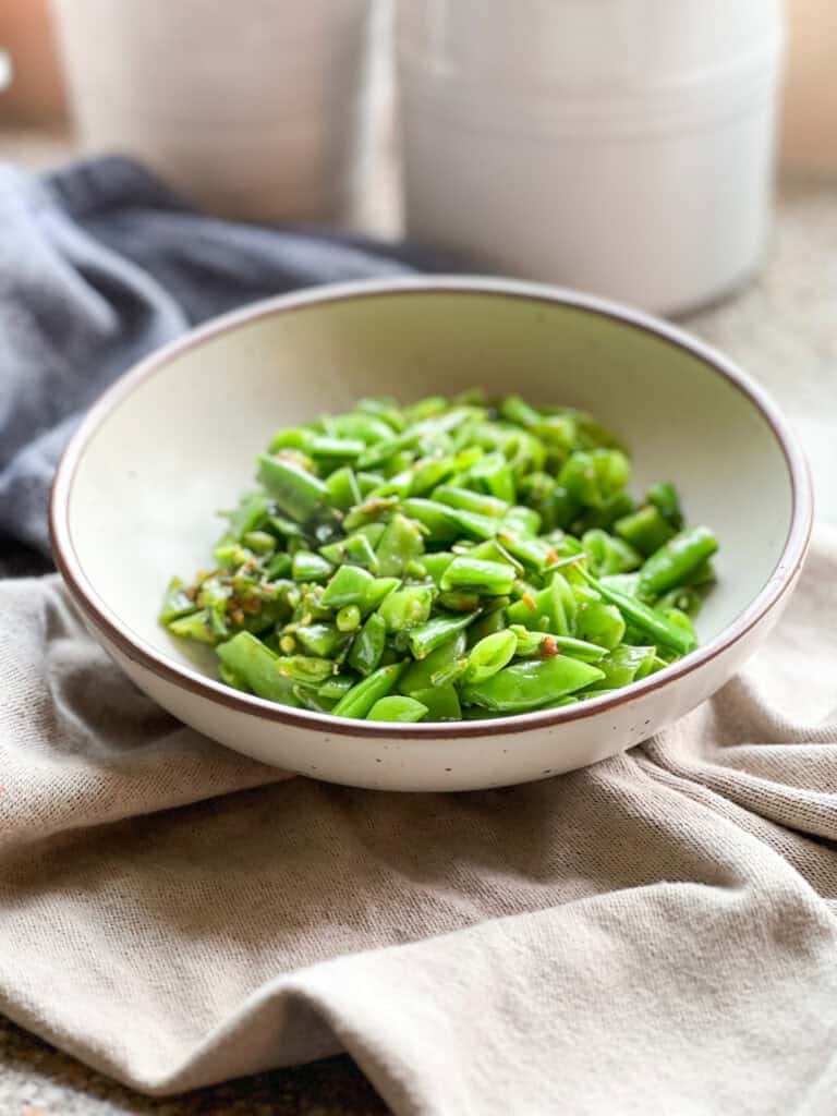 Portrait photo of sautéed sugar snap peas with fresh citrus zest and mint.