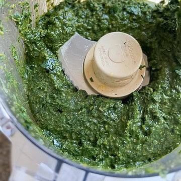 Overhead photo of the prepared basil pesto that's been processed in the food processor in preparation to store and freeze.