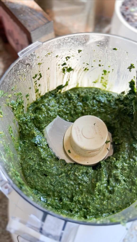 Overhead photo of the prepared basil pesto that's been processed in the food processor in preparation to store and freeze.