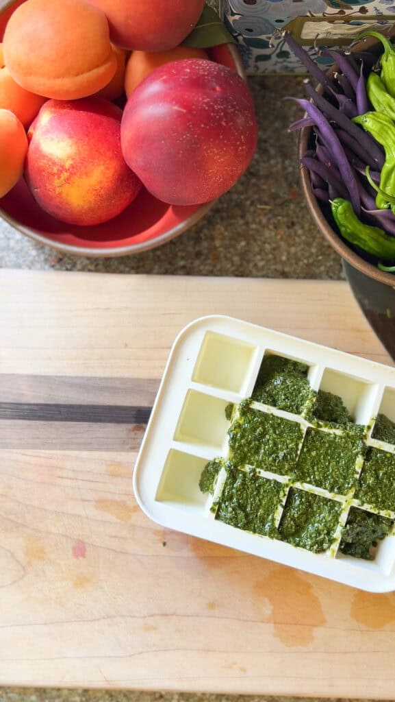 Overhead photo of the prepared basil pesto portioned out into a silicone ice cube tray for freezer storage.