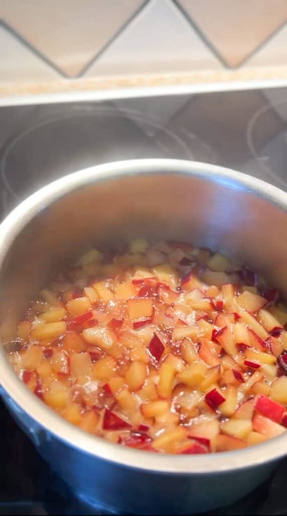 Overhead photo of the start of the cook time for the Santa Rosa Plum Compote Recipe. Amber colored flesh begins to simmer with the brown sugar simple syrup that's been infused with lavender. 