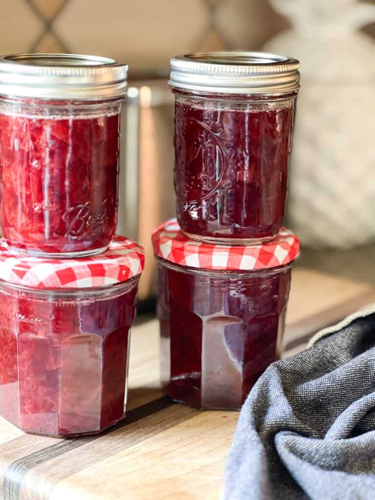 Portrait photo of four finished jars of the Santa Rosa Plum Compote Recipe. 