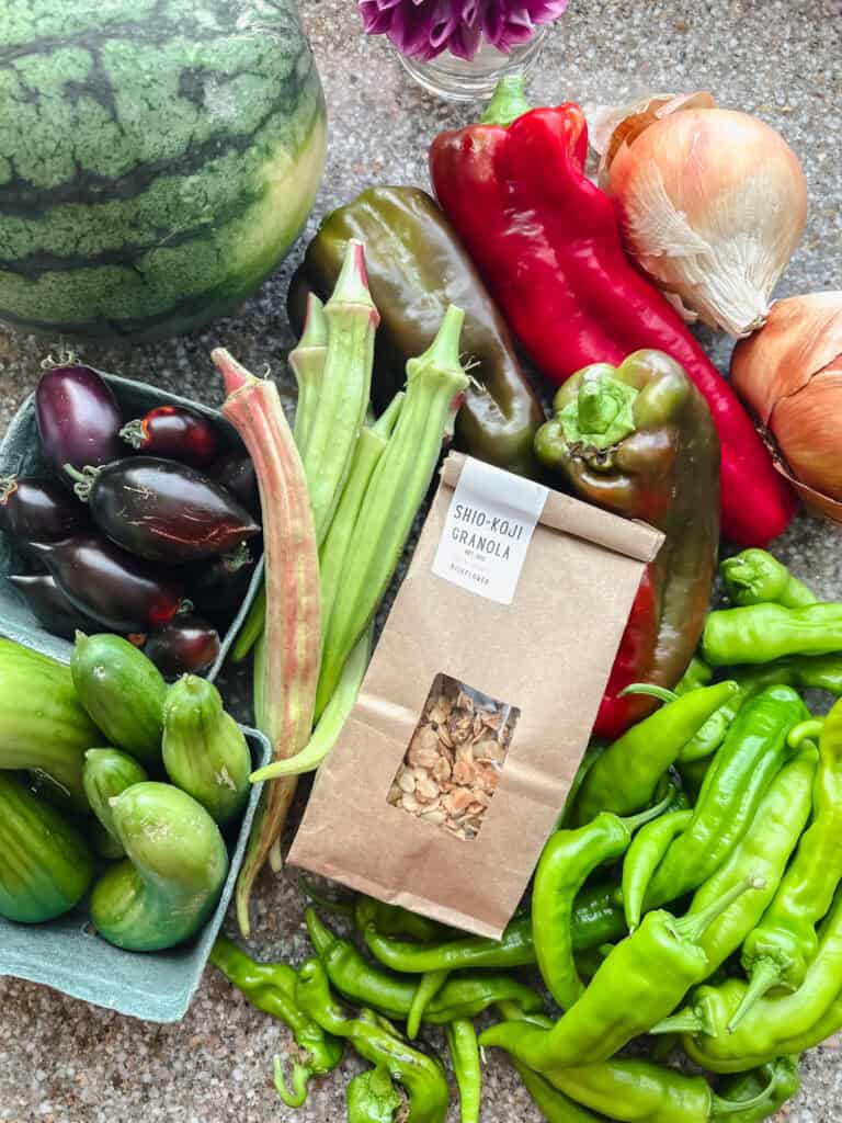 Flatlay photo of Dinner Plans Week 36 produce featuring peppers, tomatoes, cucumbers, and watermelon. 