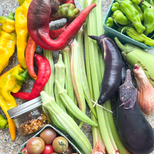 Flatlay image of CSA Week 37 box for Dinner Plans featuring tomatoes, rhubarb, okra, eggplant, and lots of peppers.