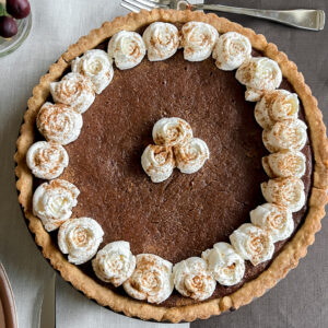 Flatlay photo of the finish Persimmon Pie Recipe garnished with Whipped Cream and a dusting of cinnamon.