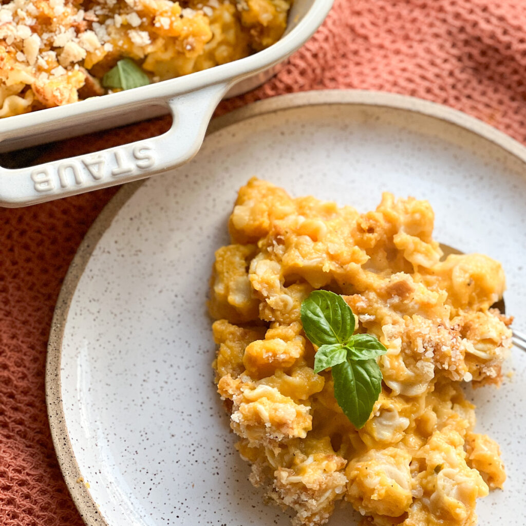 A close up shot of the Baked Butternut Squash Mac and Cheese with No Roux. A garnish of fresh basil sits atop the baked pasta.