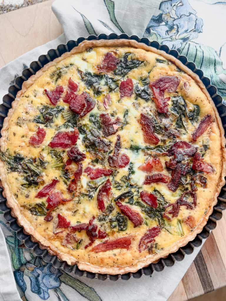 Flatlay image of a seasonal quiche filled with bacon ends, pak choi, and garleek.