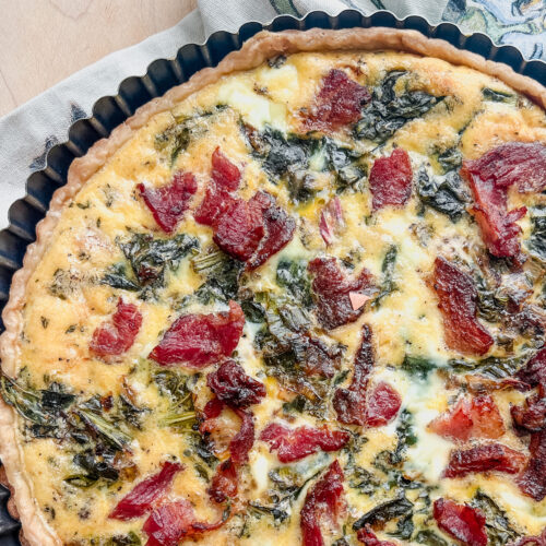 Flatlay image of a seasonal quiche filled with bacon ends, pak choi, and garleek.
