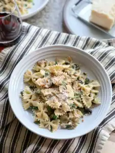 Flatlay portrait of the Late Winter Pasta with Mushrooms, Kale and Sprouting Broccoli garnished with a generous grate of parmesan cheese.