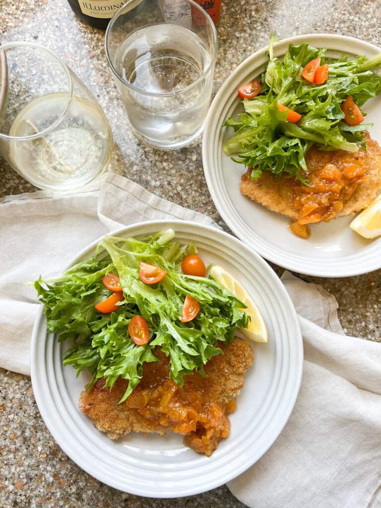 Photo of finished dish of Thin Pork Cutlets recipe with seasonal summer salad with frisee and tomatoes.