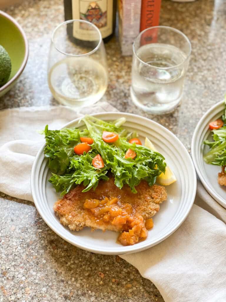 Photo of finished dish of Thin Pork Cutlets recipe with seasonal summer salad with frisee and tomatoes.
