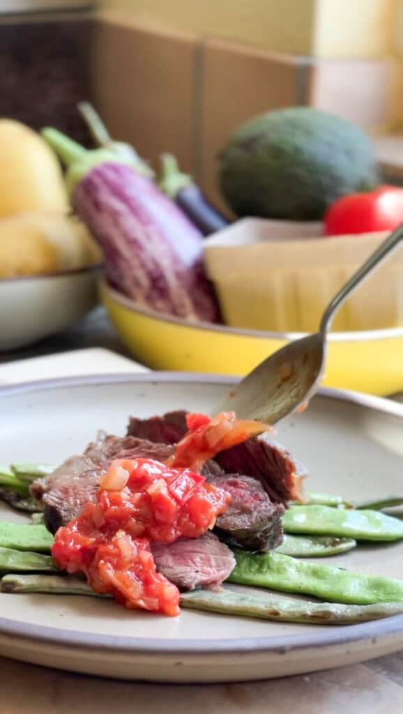 Spooning sauce over the top of grilled steak and the sauteed romano beans.